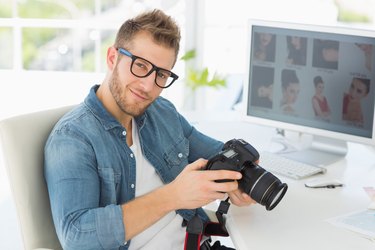 Handsome photographer holding his camera smiling at camera