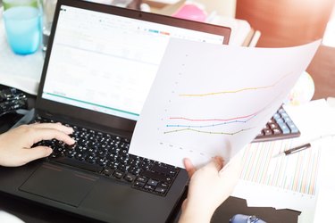 Hands of businesswoman holding analysis chart with laptop and ca