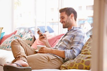 Young man sitting on sofa smiling at his phone