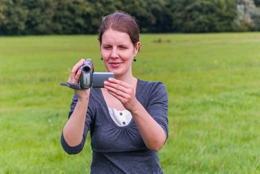 Young woman filming with a camcorder/ handycam