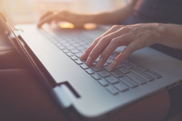 Woman working at home office hand on keyboard close up