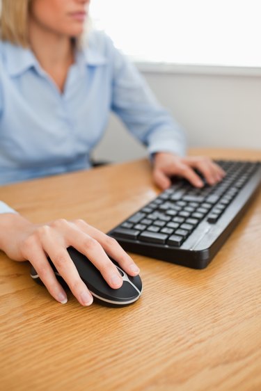 Blonde businesswoman with hands on mouse and keyboard