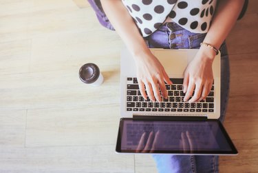 Top view of laptop in girl's hands sitting on floor