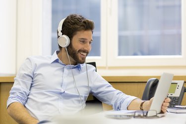 Cheerful man listening music and using computer in modern office