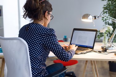 Beautiful young woman working with laptop in her office.