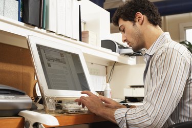 Male office worker sitting at workstation, typing