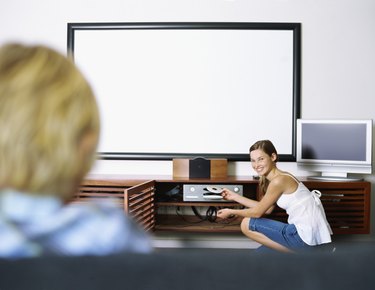 Side profile of a girl inserting a dvd into a dvd player