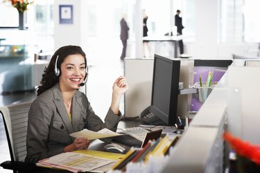 Businesswoman wearing headset at desk, smiling, portrait