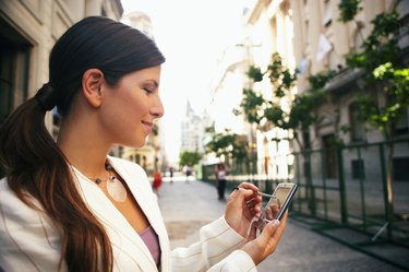 Businesswoman in street using hand held computer, smiling, close-up