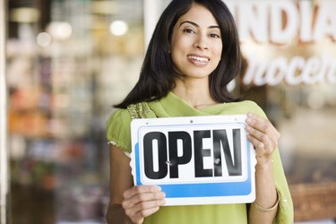 Portrait of smiling woman by storefront with open sign