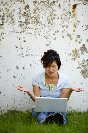 Frustrated woman on laptop computer outdoors