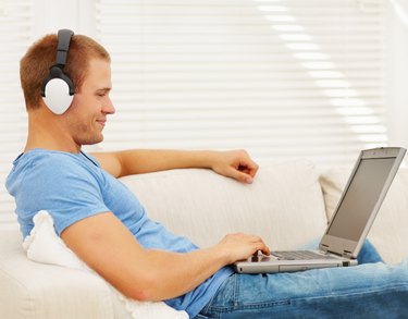 Smart young man listening to music while using a laptop