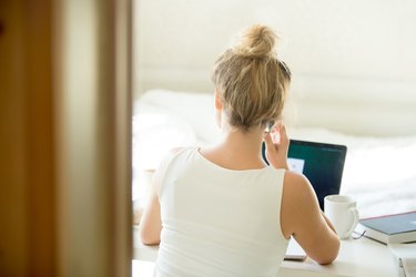 Woman sitting back talking on the phone at table.