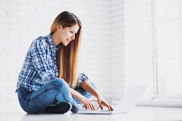 Happy student girl using laptop at home