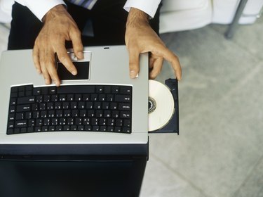 High angle view of a businessman inserting a cd into a laptop