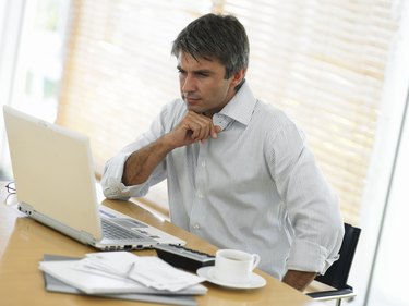 Man at desk, looking at laptop