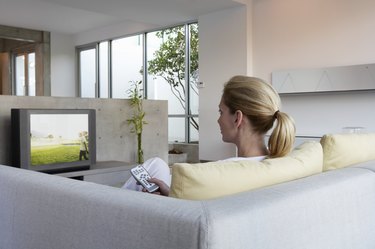 Woman relaxing on sofa watching television, rear view