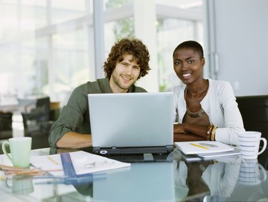 Businessman and a businesswoman sitting in front of a laptop