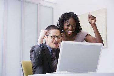 Multi-ethnic businesspeople cheering at laptop