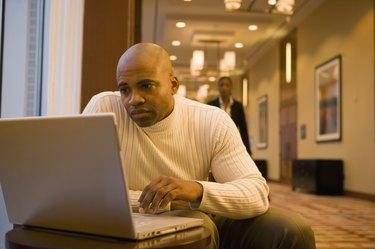 African businessman working on laptop in corridor