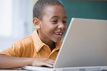 Grinning African boy typing on laptop