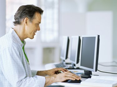 side profile of a mature man sitting in front of a computer