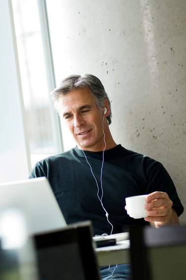 Middle-aged man listening to music in urban cafe.