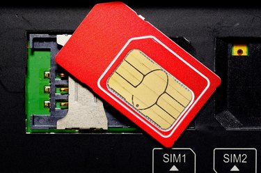 Red SIM card on slots in mobile phone.