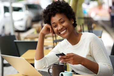 Smiling african woman at cafe with a mobile phone