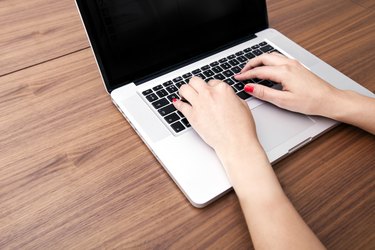 Close-up of businesswoman's hands using laptop at table