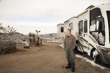 Man standing by motor home in desert with melting snow
