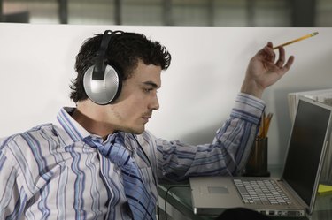 Businessman working at laptop while listening to music