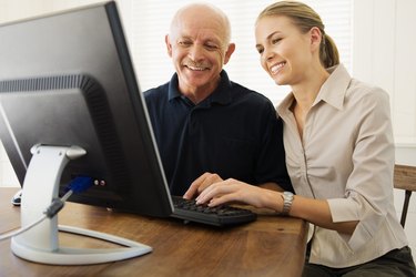 Woman helping man with computer