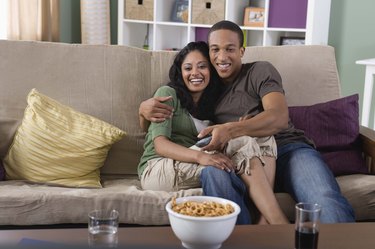 Affectionate couple watching TV at home