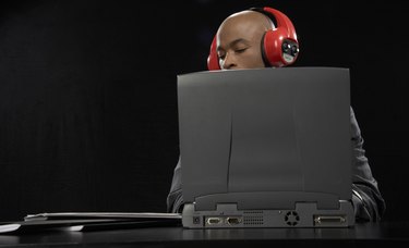 Businessman wearing headphones using laptop at desk