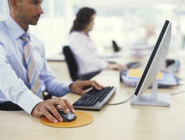 Businessman using PC, hand on mouse, side view