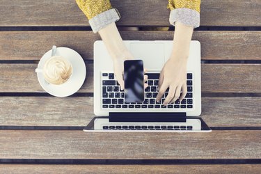 Girl with cell phone, cup of cappuccino and laptop