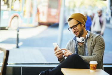 man typing text message in a coffee shop