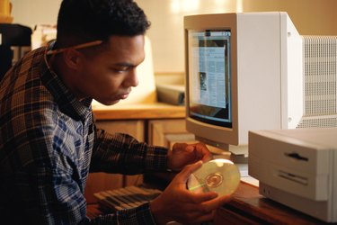 Man putting compact disc into computer