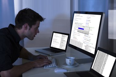 Человек, работающий с компьютером и ноутбуком