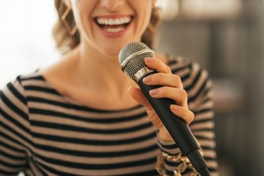 closeup on young woman singing with microphone in loft apartment