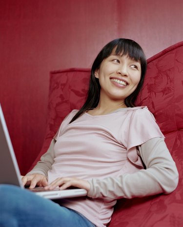 Young woman using laptop computer, smiling