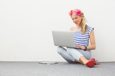 Fashion blogger sitting on the floor and using laptop