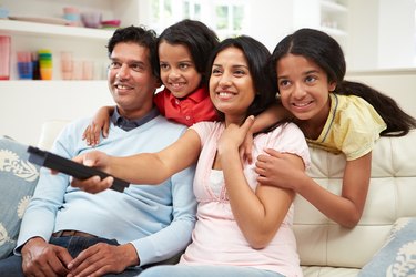 An Indian family sitting on the sofa watching television