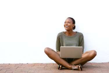 Happy african american woman sitting with laptop