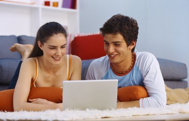 Portrait of a young couple lying on the floor and viewing a laptop