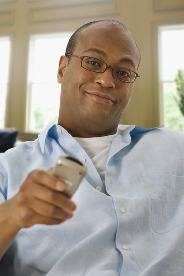 African man watching television with remote control