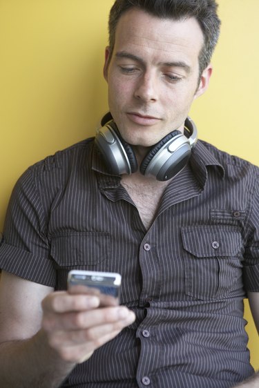 Man with headphones, reading cell phone message