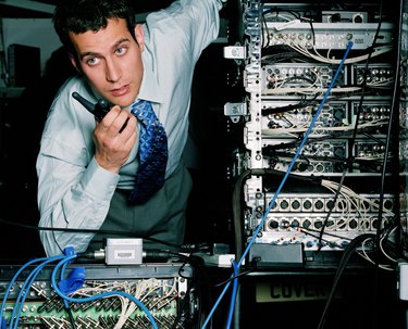 Young businessman using walkie-talkie by servers