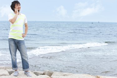 Young man using mobile phone at beach